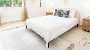 Ampia camera da letto con un letto grande, un comodino, una lampada a sospensione e vista sul verde.