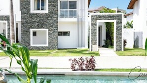 Una moderna casa a due piani con facciata in pietra, una piscina e un prato curato.