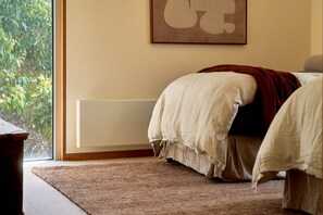 A bedroom with a bed, a window, and a radiator. - Cloudy Bay Beach House – Luxury Escape in Bruny (South Bruny)