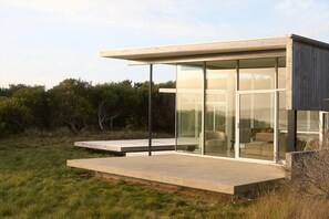 A modern house with large glass windows, a concrete deck, and a minimalist design. - Cloudy Bay Beach House – Luxury Escape in Bruny (South Bruny)
