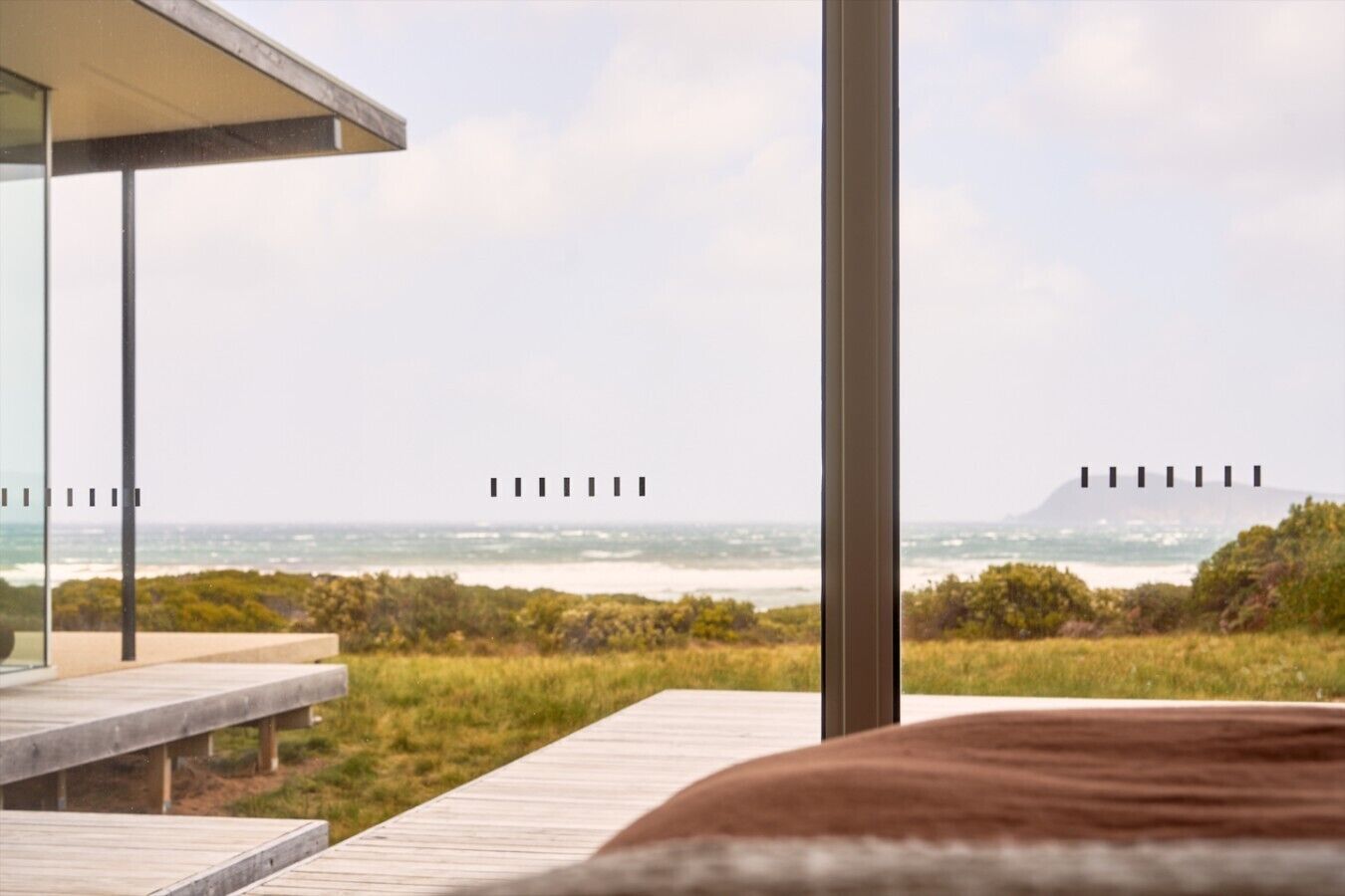 A modern outdoor seating area with a view of the ocean and a distant mountain.
