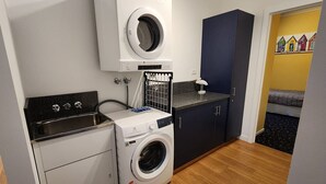 A compact laundry room with a washing machine, a dryer, and a sink. - Forest Edge - Breathtaking Views of the Hazards (Coles Bay)