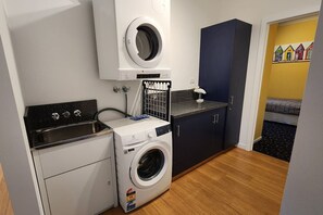 A compact laundry room with a washing machine, a dryer, and a sink. - Forest Edge - Breathtaking Views of the Hazards (Coles Bay)
