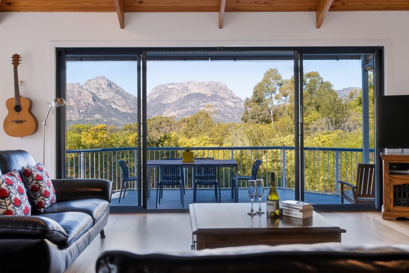 A living room with a large sliding glass door leading to an outdoor balcony with a mountain view.