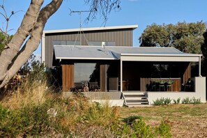 A modern two-story house with a covered outdoor area and a visible staircase leading to the entrance. - Joeys Place- Waterfront| Views| Sunsets @Freycinet (Coles Bay)
