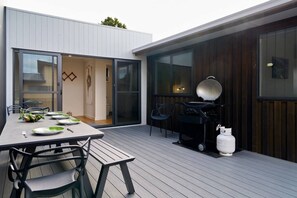 Un espace extérieur aménagé pour les repas, avec une table pour quatre personnes, un barbecue et une bouteille de gaz.