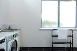 A laundry room with a washing machine, a sink, and a window with a towel rack. - Freycinet Haven! Minutes to Wineglass Bay; Sunsets (Coles Bay)