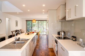 A modern kitchen with a central island, stainless steel appliances, and a view to the outdoors. - Freycinet Haven! Minutes to Wineglass Bay; Sunsets (Coles Bay)
