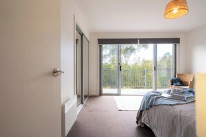 A bedroom with a bed, a chair, a balcony, and a large window. - Freycinet Haven! Minutes to Wineglass Bay; Sunsets (Coles Bay)