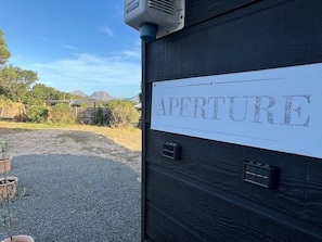 A wooden door with a sign that reads 'APERTURE' and a small electronic device mounted above it. - Aperture - 3 bedrooms house with stunning views! (Coles Bay)