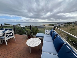 A deck with a table and chairs, a round table, and a sofa with cushions. - Aperture - 3 bedrooms house with stunning views! (Coles Bay)