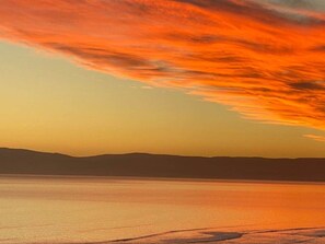 A calm body of water with a distant mountain range and a sunset sky. - Aperture, Stunning Views Frame Your Escape (Coles Bay)