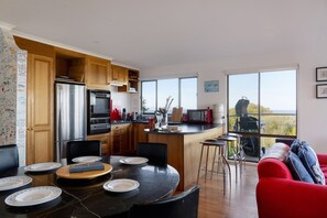 Une cuisine moderne dotée d’un îlot central, de meubles en bois et d’un coin repas avec un canapé rouge et des tabourets de bar.