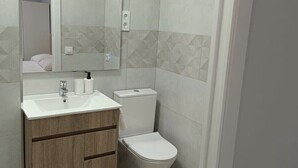 Un baño moderno con lavamanos, espejo, inodoro y mueble de madera.