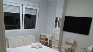Un dormitorio moderno con cama, mesitas de noche, escritorio y una silla.