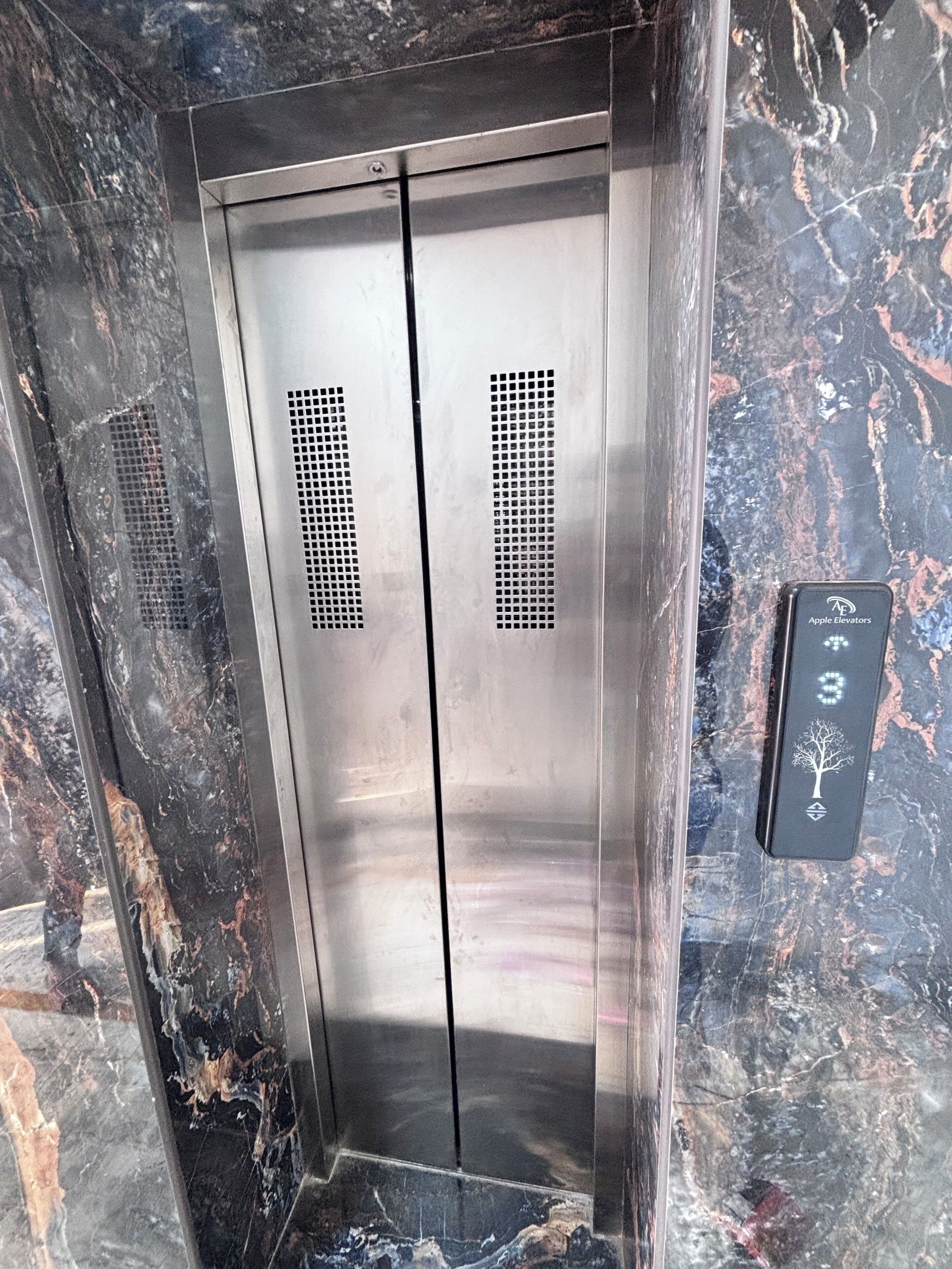 A metallic elevator with a control panel displaying the number 3.