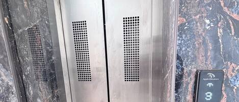 A metallic elevator with a control panel displaying the number 3.
