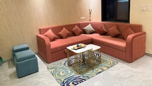 A modern living room with a sectional sofa, a small coffee table, and a patterned rug. - Sk Govindam (Jaipur)