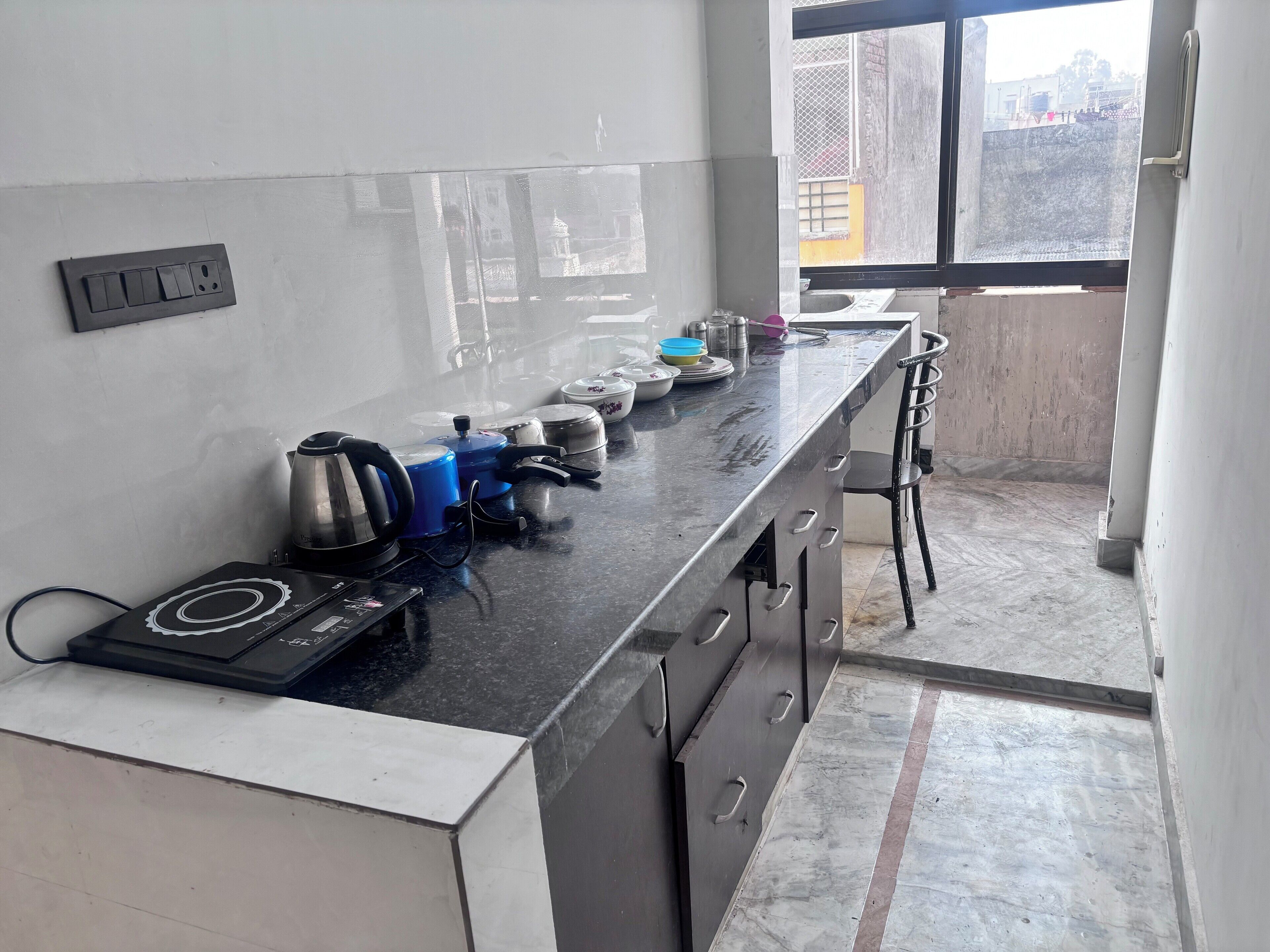 A kitchen with a black countertop, a kettle, a blue pot, and a sink.
