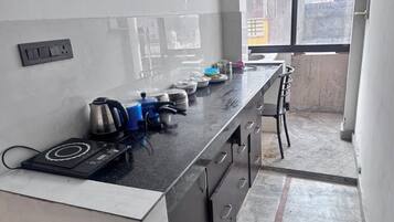 A kitchen with a black countertop, a kettle, a blue pot, and a sink.