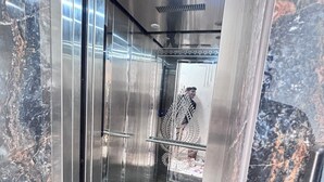 An elevator interior with reflective metallic walls and a marble floor. - Sk Govindam (Jaipur)