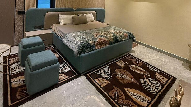 A modern bedroom with a bed, seating area, and a large window. - Sk Govindam (Jaipur)