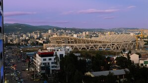 A stadium with a unique roof structure, surrounded by urban buildings and a busy street. - Daisy Hotel (Addis Ababa)