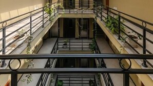 A multi-level atrium with a glass ceiling, railings, and potted plants. - Daisy Hotel (Addis Ababa)