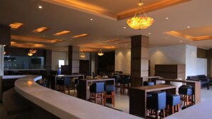 A modern restaurant with a curved counter, multiple seating areas, and pendant lighting. - Daisy Hotel (Addis Ababa)