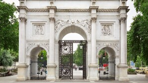 A large, ornate stone archway with intricate carvings and a central black gate.