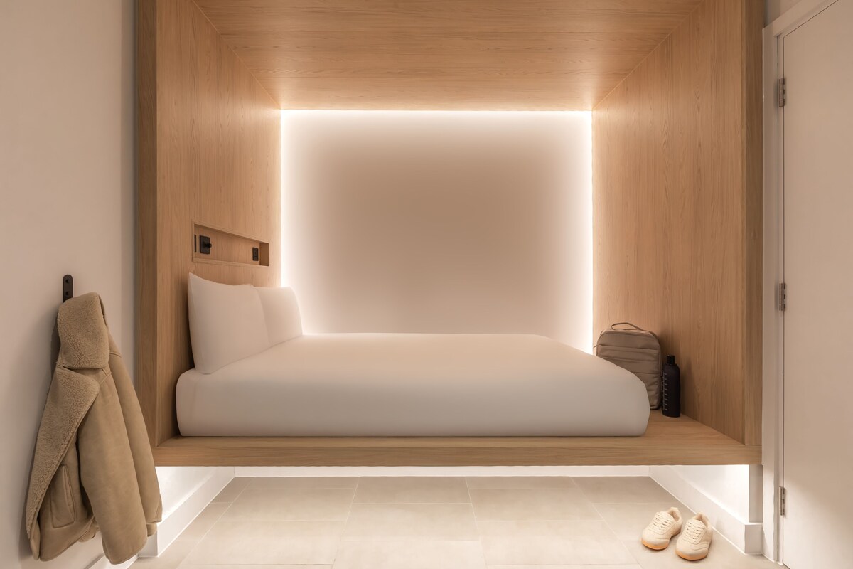 Un dormitorio moderno con cama empotrada, almacenaje junto a la cama y perchero.