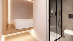 A modern bathroom with a glass-enclosed shower, a toilet, and a bed with built-in lighting.