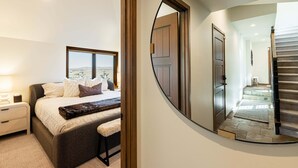 Een slaapkamer met een groot bed, nachtkastjes, een spiegel en uitzicht op buiten.
