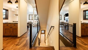 Een modern interieur met een houten trap, een keuken en uitzicht op de verdieping erboven.