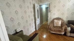A living room with a green sofa, a patterned armchair, and a wooden floor. - Qesr Town Hotel (Baku)
