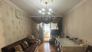 A dining area with a wooden floor, a dining table with chairs, a chandelier, and a sofa with patterned cushions. - Qesr Town Hotel (Baku)