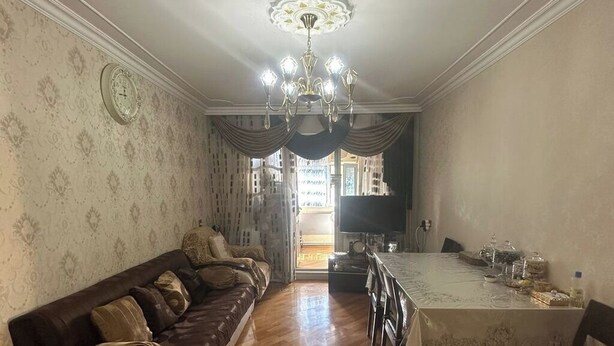 A dining area with a wooden floor, a dining table with chairs, a chandelier, and a sofa with patterned cushions. - Qesr Town Hotel (Baku)