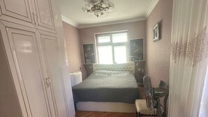 A bedroom with a bed, a desk, a chair, a wardrobe, and a window. - Qesr Town Hotel (Baku)