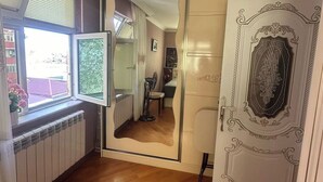 A room with a large mirror, a radiator, a window with blinds, and a door with ornate detailing. - Qesr Town Hotel (Baku)
