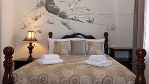 A neatly made bed with a patterned bedspread, a wall mural, a bedside lamp, and a wooden nightstand. - Capital Luxury Rooms Split (Split)