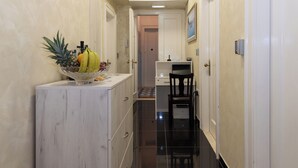 A hallway with a marble counter, a black chair, and a small table with fruits and condiments. - Capital Luxury Rooms Split (Split)