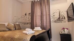 A hotel room with a bed, pillows, a TV, a small table with a vase and flowers, and a wall with a mural. - Capital Luxury Rooms Split (Split)