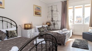 A bedroom with two beds, a large window with curtains, a ship decoration, and a view of buildings outside. - Capital Luxury Rooms Split (Split)