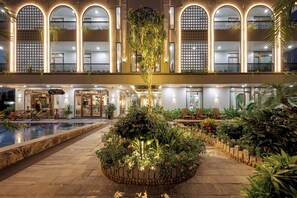 A hotel courtyard with a pool, seating areas, and a central garden with plants and lights. - Pataco Tam Coc Hotel (Nam Hoa Lu)