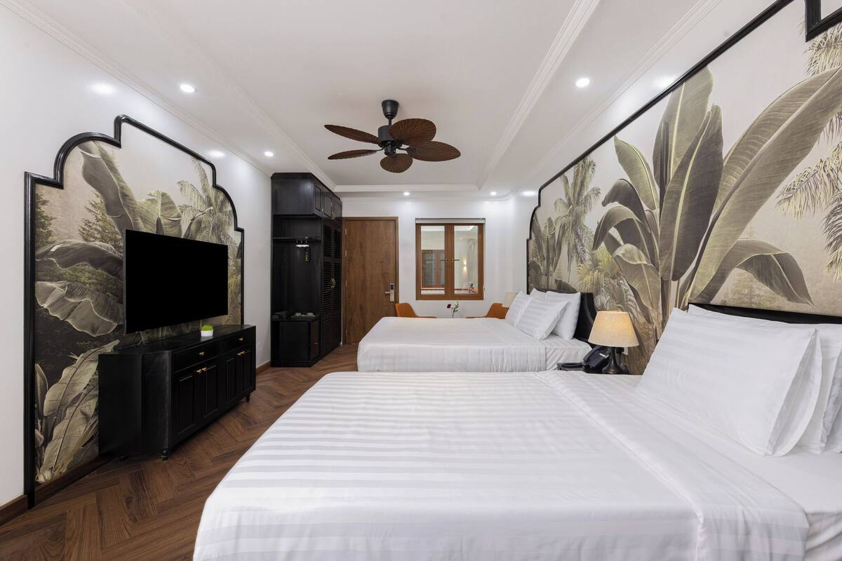 A hotel room with two beds, a TV, a ceiling fan, and a large window.