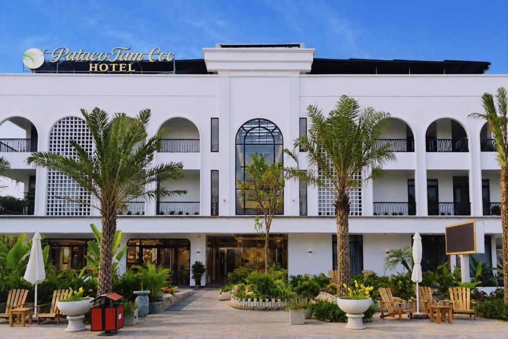 A hotel with a white facade, multiple balconies, and a central entrance.