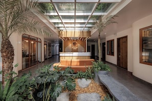 A modern hotel lobby with a central seating area, a glass ceiling, and tropical plants. - Pataco Tam Coc Hotel (Nam Hoa Lu)