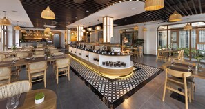 A modern restaurant with a central bar, wooden furniture, and pendant lighting. - Pataco Tam Coc Hotel (Nam Hoa Lu)