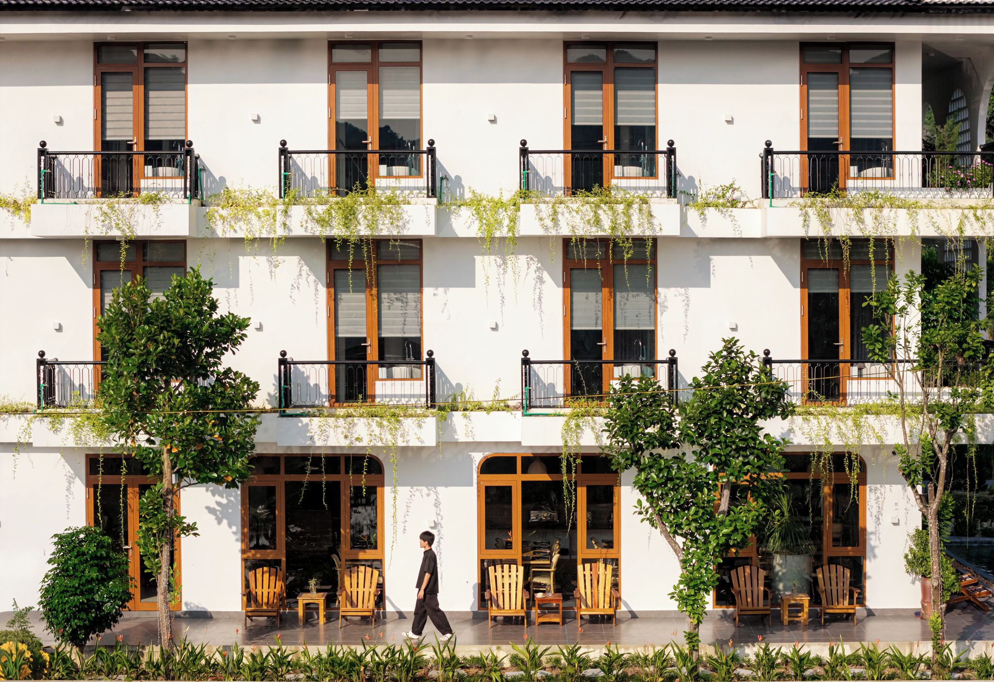 A multi-story building with balconies, wooden furniture, and greenery.
