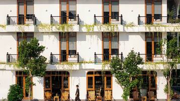 A multi-story building with balconies, wooden furniture, and greenery.